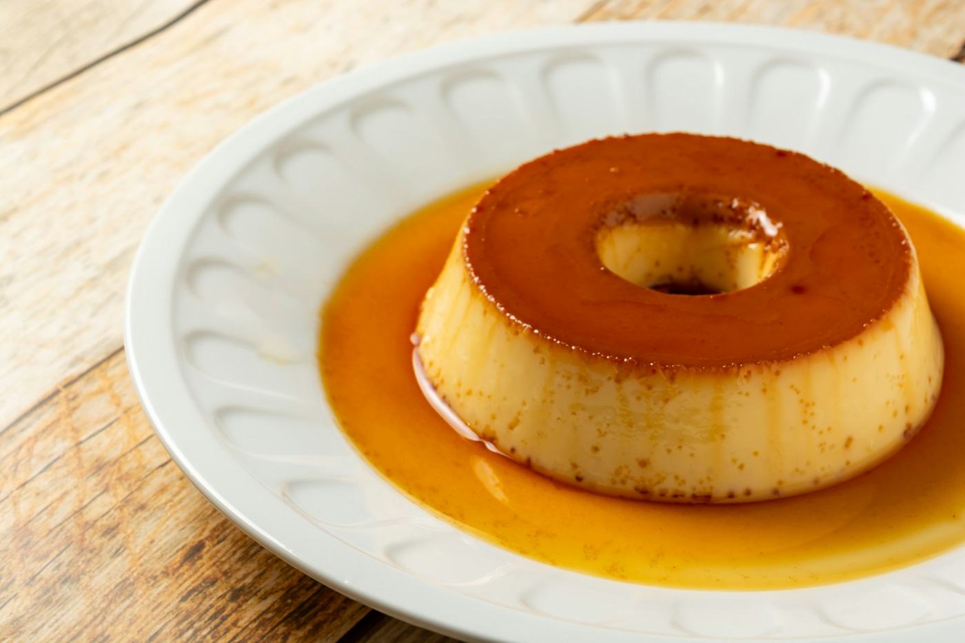Pudim de leite com calda de caramelo em prato branco